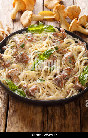 Italienische Spaghetti mit gebratenen Pfifferlingen in einer cremigen Käse sauce Close-up auf einem Teller auf den Tisch. Vertikale Stockfoto