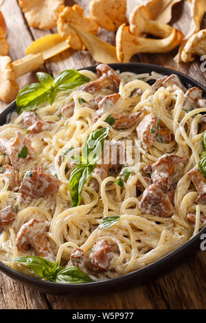 Spaghetti mit Pfifferlingen in Sahnesauce mit Basilikum close-up auf einem Teller auf den Tisch. Vertikale Stockfoto