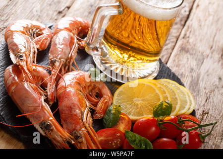 Köstliche Garnelen mit hellen Bier, Zitronen und Tomaten close-up auf einer Schiefertafel Board auf dem Tisch. Horizontale Stockfoto
