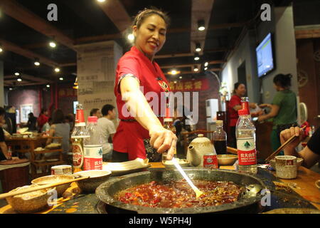 ---- Eine chinesische Kellnerin bedient Kunden einen würzigen heißen Topf auf einen hotpot Restaurant in Chongqing, China, 15. September 2017 zu genießen. Stockfoto