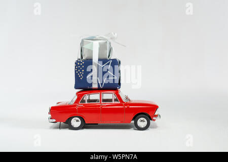 Red vintage Spielzeugauto mit einem Weihnachtsgeschenke in Kartons auf dem Dach. Isolierte Bild auf weißem Hintergrund. Stockfoto