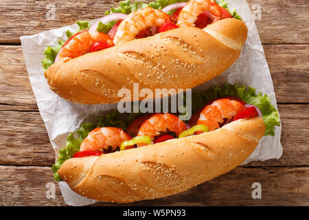 Frisches Sandwich mit Riesengarnelen, Gemüse close-up auf Pergament auf den Tisch. horizontal oben Ansicht von oben Stockfoto