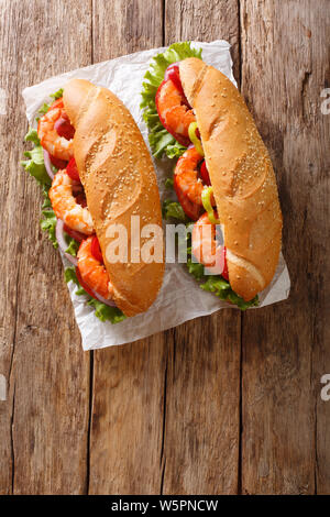 Lecker Sandwich mit Garnelen und Gemüse close-up auf Pergament auf den Tisch. Vertikal oben Ansicht von oben Stockfoto