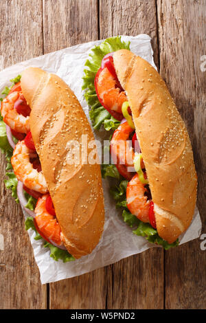 Frisches Sandwich mit Riesengarnelen, Gemüse close-up auf Pergament auf den Tisch. Vertikal oben Ansicht von oben Stockfoto