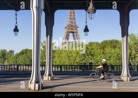Paris mit dem Fahrrad - eine Frau tragen Helm Radfahren über die Bir Hakeim Brücke in Paris, Frankreich, Europa. Stockfoto