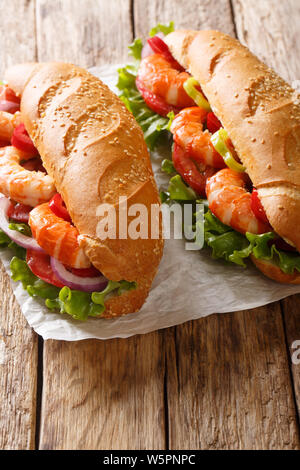 Frisches Sandwich mit Riesengarnelen, Gemüse close-up auf Pergament auf den Tisch. Vertikale Stockfoto