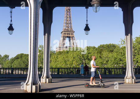 Paris Elektroroller - ein Mann auf einem Elektroroller reiten über die Bir Hakeim Brücke in Paris, Frankreich, Europa. Stockfoto