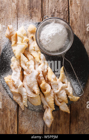 Frisch Angel Wings Plätzchen mit Puderzucker close-up auf den Tisch. Vertikal oben Ansicht von oben Stockfoto