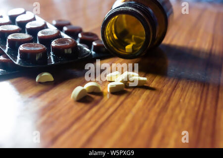 Schließen Öffnen Glasfläschchen mit Medizin Pillen oder Tabletten im Blister auf hölzernen Tisch Hintergrund. Apotheke Heilung und Gesundheit Konzept. Selec Stockfoto