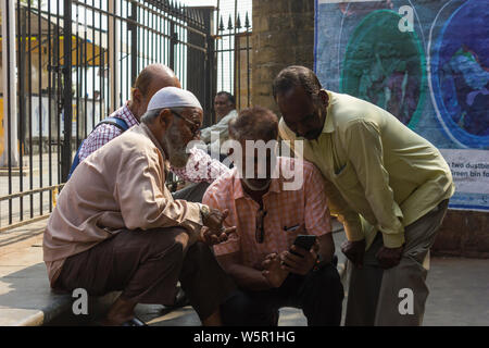 Mumbai, Maharashtra, Indien - 05-10-2019. Männer verschiedener Religion Kontrolle cricket Kerbe in einem Handy. Einheit in der Vielfalt. Stockfoto