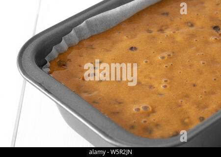 Fruit Cake Laib Mischung in einem Metall Backform. Auf einem weißen Holz Hintergrund Stockfoto