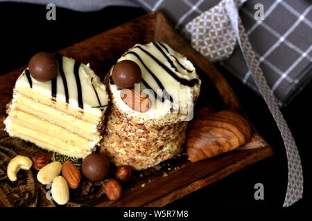 2 überlagerte weiße Schokolade und Nüsse keto Dessert auf dunklem Holz Tablett serviert, mit Mandeln und verschiedenen Nüssen dekoriert. Alternative ketogenic Diät. Stockfoto