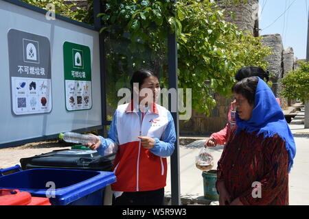 Eine chinesische Freiwillige stellt Müll sortieren Dorfbewohner in Dongchu Dorf, Stadt Rongcheng, Provinz Shandong im Osten Chinas, 4. Juni 2019. Verschiedene Stockfoto