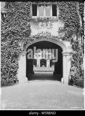 Haupteingang, innerhalb, Schloss Cecilienhof, Potsdam, Deutschland, dem Schauplatz der Potsdamer Konferenz. Es ist das ehemalige Schloss der Frau von Wilhelm II., deutscher Kronprinz. Wappen der Familie ist über dem Bogen gesehen. Innerhalb der geschwungene Auffahrt kann ein riesiger Stern der roten Blumen, die von den Sowjets gepflanzt gesehen werden. Stockfoto