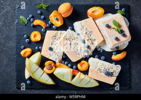 In der Nähe von Schmelz Semifreddo alle Mandorle, sizilianischen Almond apricot Melone Semifreddo auf einer Schiefertafel Teller mit Früchten und Beeren serviert, Ansicht von abov Stockfoto