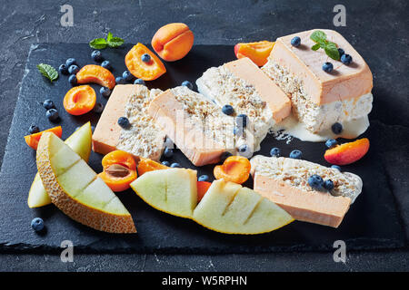 Italienischen sommers Dessert, schmelzen Semifreddo alle Mandorle, sizilianischen Almond apricot Melone Semifreddo auf einer Schiefertafel Teller mit Früchten und Beeren serviert, vi Stockfoto