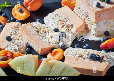 Italienischen sommers Dessert, schmelzen Semifreddo alle Mandorle, sizilianischen Almond apricot Melone Semifreddo auf einer Schiefertafel Teller mit Früchten und Beeren serviert, vi Stockfoto