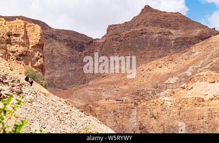 Wanderer genießen Sie die Wanderwege auf den Klippen und Berge von Ein Gedi finden oberhalb der David Bach mit mount Yishay im Hintergrund Stockfoto