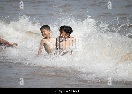 Warmes Wetter in Skegness. Jungen spielen in den Wellen auf Skegness Beach Stockfoto