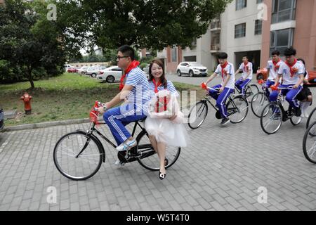 Chinesische Paar dar, da sie eine Yongjiu Fahrrad während einer Hochzeit in Suzhou Stadt fahren, der ostchinesischen Provinz Jiangsu, 16. Juni 2019. Ein paar Stockfoto