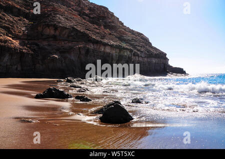 Ruhige Landschaft der natürlichen und unberührten Strand Tiritaña. Bucht umrahmt von hohen Klippen in Barranco in der Nähe von Taurito/Mogan. Zwischen der Punta de la Cruz de Piedra ein Stockfoto