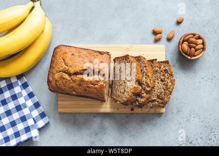 Bananenbrot mit Muttern in Scheiben geschnitten auf konkrete Tabelle Hintergrund. Tabelle Ansicht von oben Stockfoto