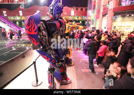 Ein Student trägt einen zwei Meter hohen lebensgroße Nachbildung von Megatron ist seitens der Kunden in ein Einkaufszentrum in der Stadt Xi'an im Nordwesten Chinas umgeben Stockfoto