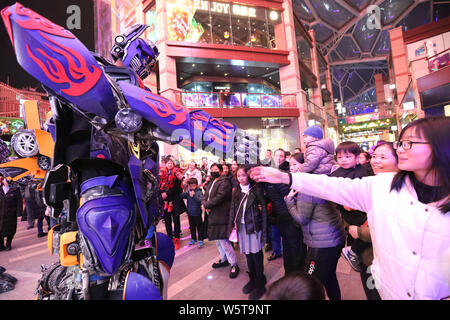 Ein Student trägt einen zwei Meter hohen lebensgroße Nachbildung von Megatron ist seitens der Kunden in ein Einkaufszentrum in der Stadt Xi'an im Nordwesten Chinas umgeben Stockfoto