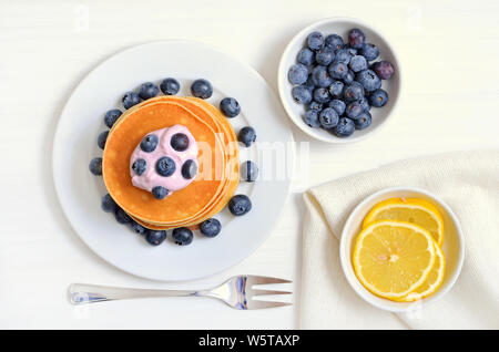 Pfannkuchen mit Heidelbeeren auf weiße Platte, frische Heidelbeeren in Schale, Ansicht von oben Stockfoto