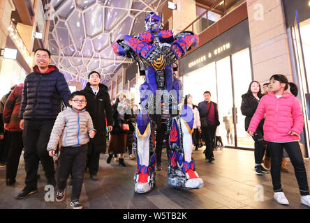 Ein Student trägt einen zwei Meter hohen lebensgroße Nachbildung von Megatron ist seitens der Kunden in ein Einkaufszentrum in der Stadt Xi'an im Nordwesten Chinas umgeben Stockfoto