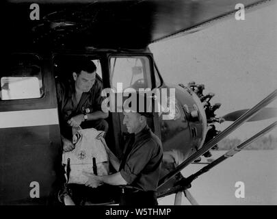 Foto: Bezirk Ranger Jack Valentine; Umfang und Inhalt: Original Bildunterschrift: Dist. Ranger Jack Valentine (LaCroix R.D.) Übergabe einen Rucksack mit Feuer Schlauch an F.S. pilot Merle Moltrup Wer ist das Laden von Brandschutzanlagen in der Kabine von F.S. Stinson Eindecker (siehe Nr. 400350). Stockfoto
