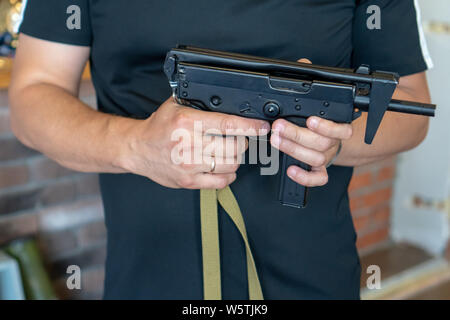 Russland, Tatarstan, 23. Juni 2019. PP-91 Kedr Maschinenpistole. Ein Mann hält ein Maschinengewehr in der Hand auf dem Hintergrund einer braunen Wand. Stockfoto