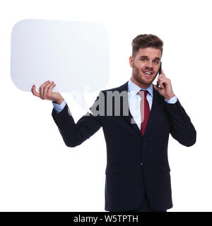Junge Unternehmer am Telefon hält Sprechblase beim Stehen auf weißen Hintergrund, Porträt Bild. Er trägt ein Marine Anzug und einem roten Stockfoto