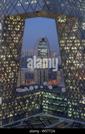 Eine Nacht der neue Hauptsitz der People's Daily durch die neuen CCTV-Tower im Central Business District (CBD) in Peking gesehen, Stockfoto