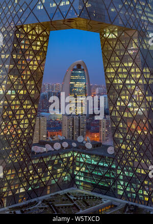 Eine Nacht der neue Hauptsitz der People's Daily durch die neuen CCTV-Tower im Central Business District (CBD) in Peking gesehen, Stockfoto