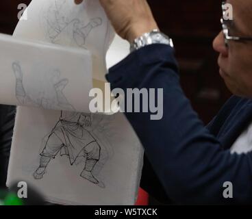 Ein Mitarbeiter zeigt die Handschriften der Sondermarken zum Thema "Zeichen in Jin Yongs Romane in einer Filiale von Hongkong Post in Hongkong, China, Stockfoto