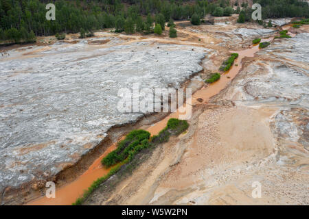 Antenne top down Sicht; Drohne über eine sehr verschmutzten Fluss mit kupferfarbenen Wasser fliegen; Dumping von chemischen Abfällen in den Fluss; tote Vegetation, tr Stockfoto