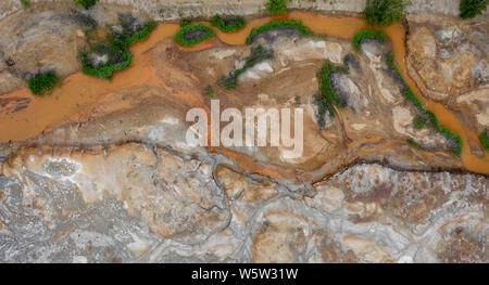 Antenne top down Sicht; Drohne über eine sehr verschmutzten Fluss mit kupferfarbenen Wasser fliegen; Dumping von chemischen Abfällen in den Fluss; tote Vegetation, tr Stockfoto