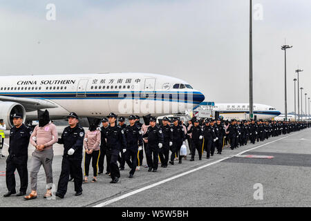 Chinesische Verdächtige für Cross-border telecom Betrug durch chinesische Polizisten begleitet, wie sie sich aus Kambodscha zurück und kommen an der Stockfoto