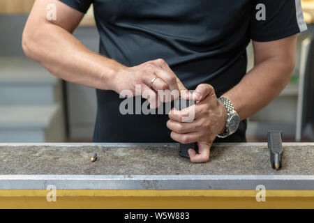 Ein Mann in einem schwarzen T-Shirt Gebühren die Pistole Halter mit 9 19 Patronen Stockfoto