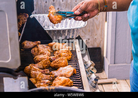 African American nigerianischen Mann grillen braten Huhn Oberschenkel am Grill Stockfoto