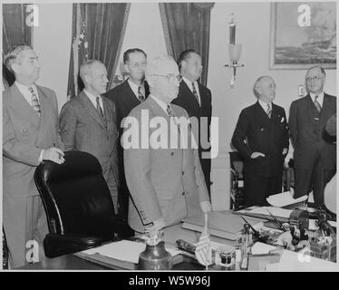 Foto von Präsident Truman, der an seinem Schreibtisch im Oval Office, mit Mitgliedern seines Kabinetts in der Nähe stehen, anlässlich des George C. Marshall's Vereidigung als neuer Staatssekretär. Stockfoto