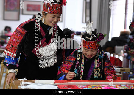 Chinesische Frau Liu Ying von Miao ethnische Gruppe beauftragt eine handwerkerin ein Kunstwerk von Miao Stickerei an Ihre Werkstatt in Kaili Stadt zu schaffen, im Südwesten von C Stockfoto