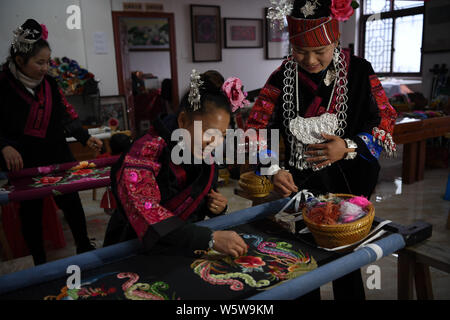 Chinesische Frau Liu Ying von Miao ethnische Gruppe beauftragt eine handwerkerin ein Kunstwerk von Miao Stickerei an Ihre Werkstatt in Kaili Stadt zu schaffen, im Südwesten von C Stockfoto