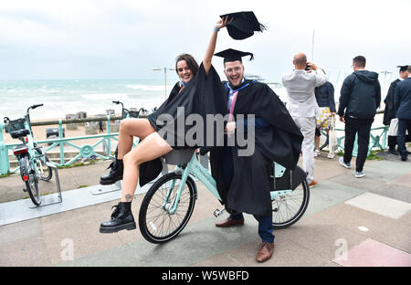 Brighton, Großbritannien. 30.. Juli 2019. Die Studenten feiern ihren Erfolg mit ihrem Abschluss an der University of Brighton an einer windigen Küste nach der Zeremonie. Quelle: Simon Dack/Alamy Live News Stockfoto