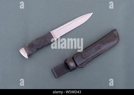 Schwarze Armee Messer auf einem grauen Hintergrund. Messer und schwarze Lederhülle close-up. Stockfoto