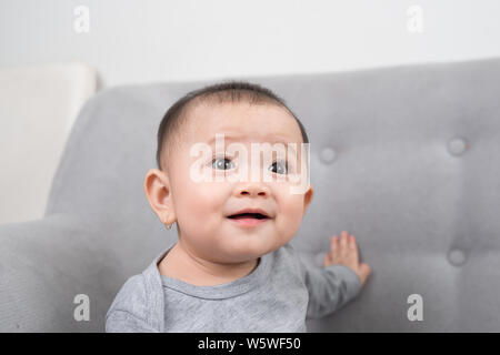 Kindheit, Säuglingsalter und Personen Konzept - glückliches kleines Mädchen auf dem Sofa zu Hause sitzen Stockfoto