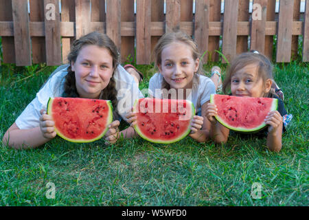 Drei Schwestern Sommer portrait. lächelnd Kinder outdoor. Kinder mit Wassermelone. Drei glücklich lächelnde Kind essen Wassermelone im Park. Konzept der Summe Stockfoto