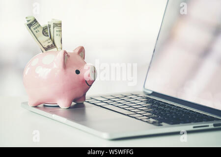 Sparschwein mit Laptop auf dem Schreibtisch, Online Shopping Konzept Stockfoto