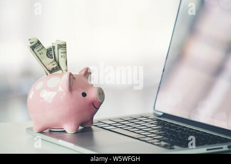 Sparschwein mit Laptop auf dem Schreibtisch, Online Shopping Konzept Stockfoto